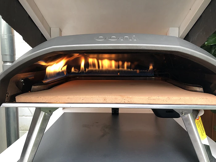 Biscotto stone placed in Ooni Koda 16 with lit gas flames in the background